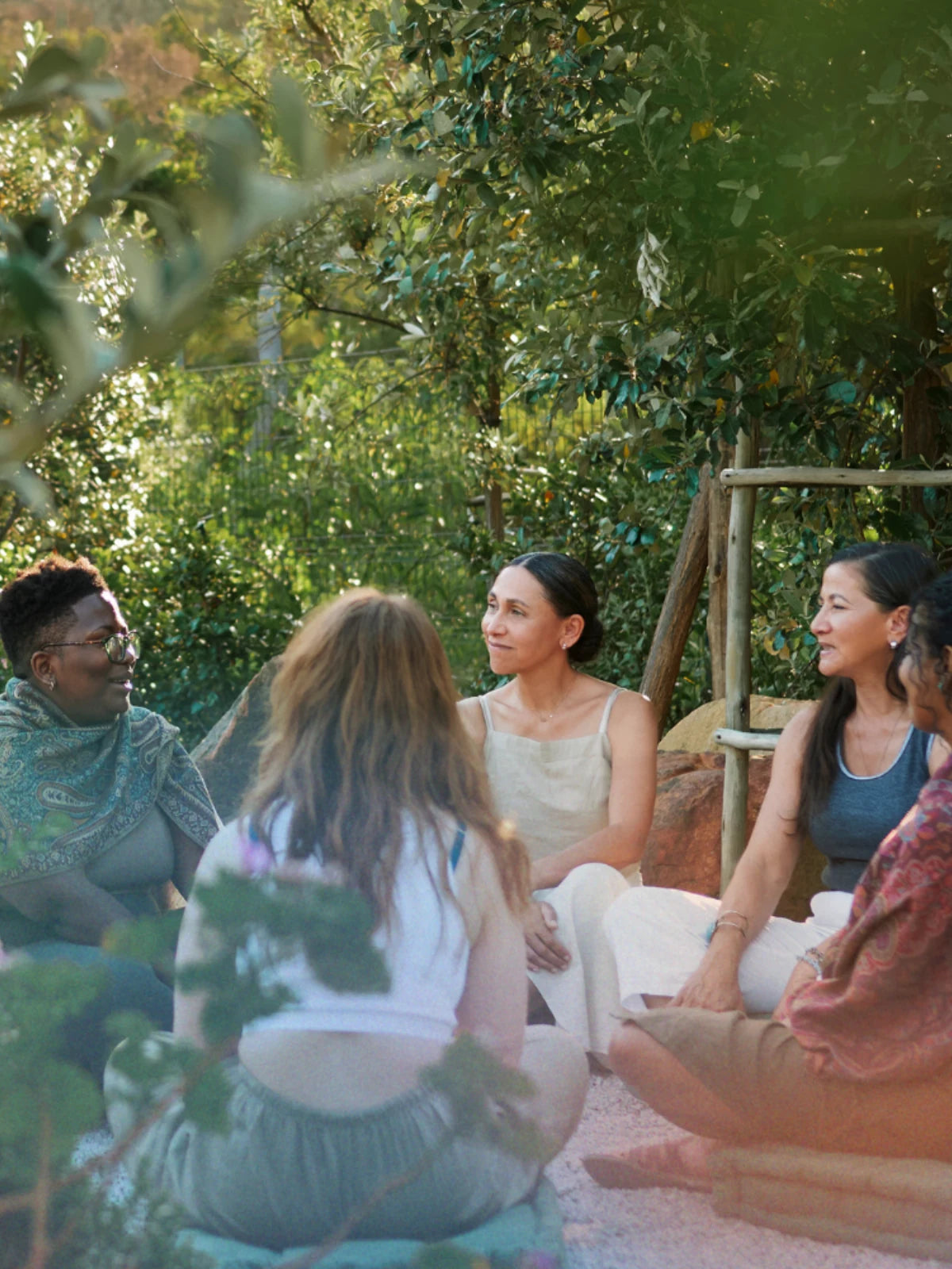 Gesprächsrunde im sonnigen Garten: Teilnehmende sitzen entspannt im Kreis zwischen grünen Bäumen