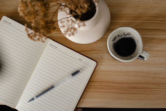 4-DMC Erfahrungsbericht – Aufgeschlagenes Notizbuch mit Stift neben einer Tasse Kaffee auf einem Holztisch