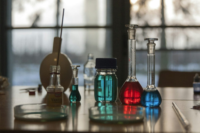 Dosierung von 4-DMC – Laborkolben und Glasgefäße mit farbigen Flüssigkeiten auf einem Labortisch