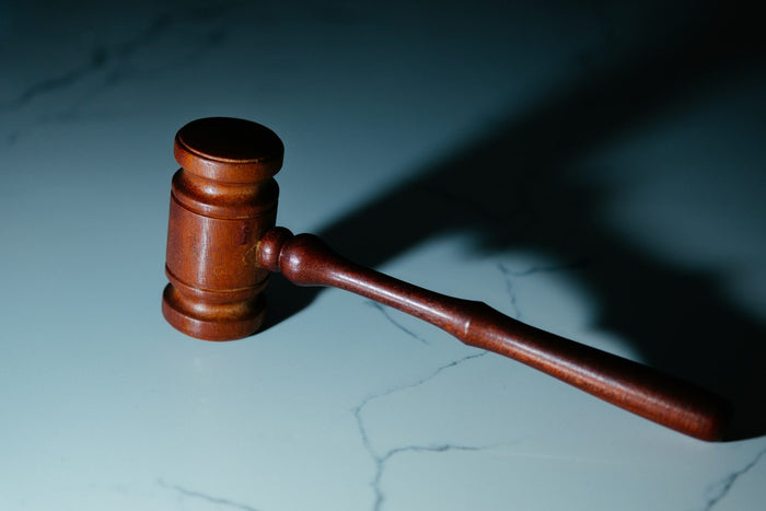 Legalität von 4-DPV – Hölzerner Richterhammer auf Marmoroberfläche mit langem Schatten