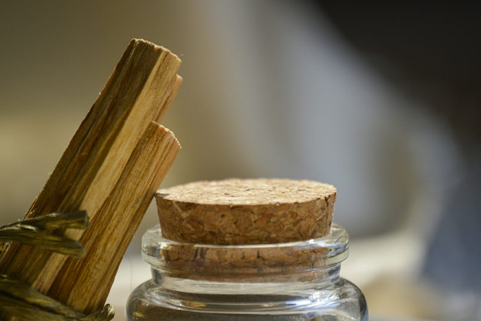 Palo Santo räuchern – helle Palo-Santo-Hölzer neben einem Glas mit Korkdeckel